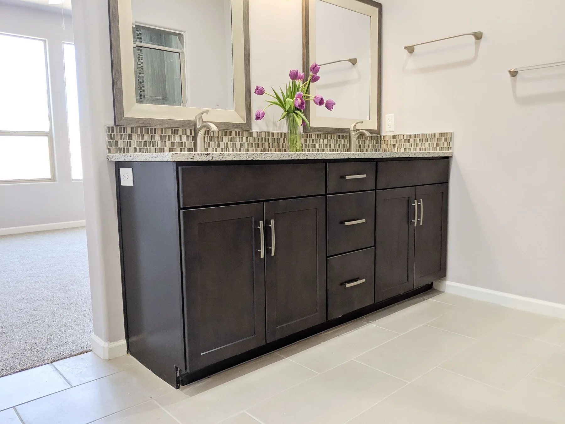 Bathroom vanity with a stone top and framed mirrors