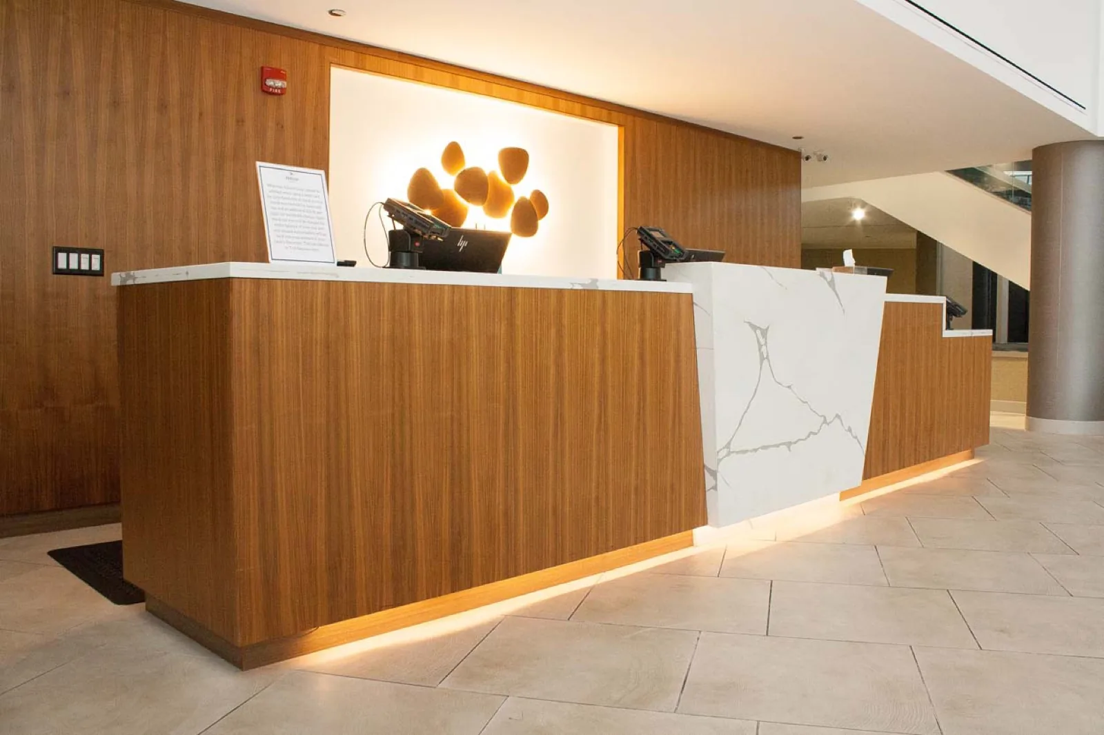 Commercial reception desk in wood veneer with a stone end panel