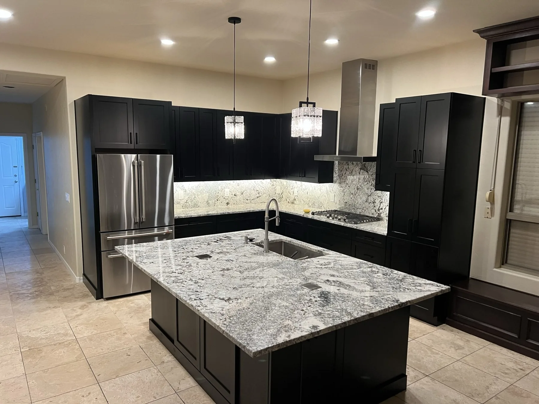 Black kitchen cabinetry with a stone island, built by Beyond Cabinets by Mueller