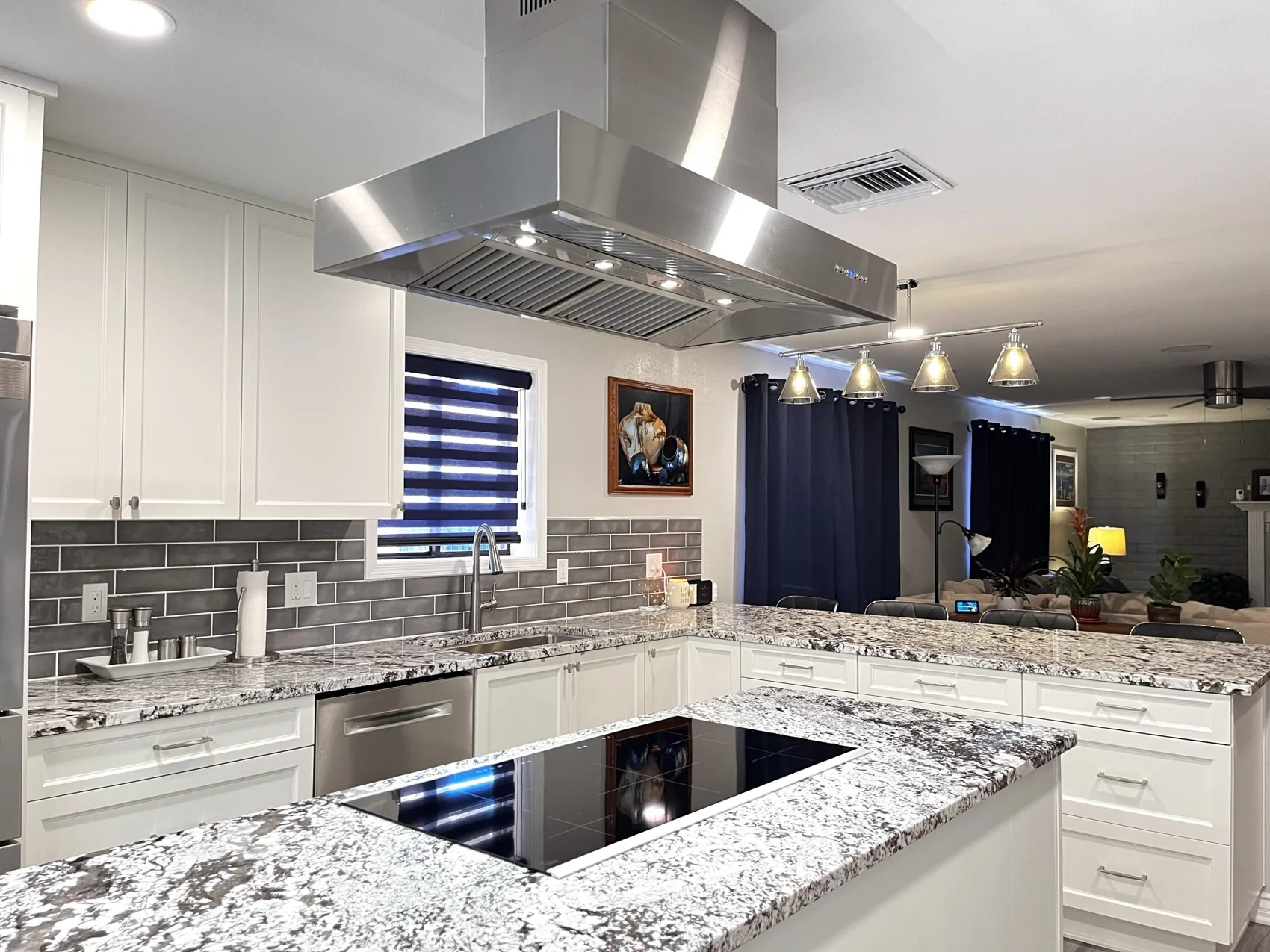 White kitchen with a stone island and a stainless island hood