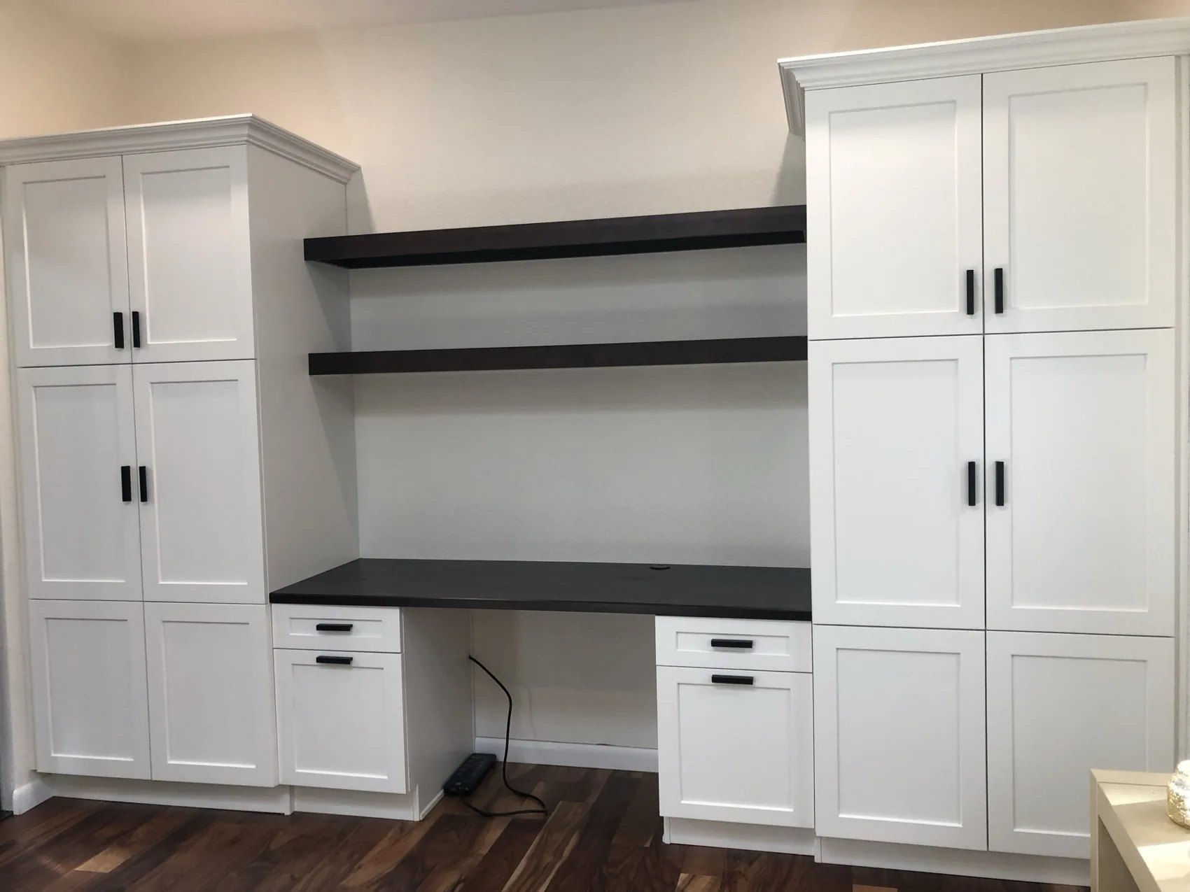 White home office built-in with a dark desk surface and floating shelves